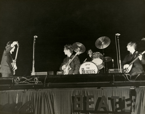 The Beatles on stage at the Gator Bowl showing the four with their instruments.