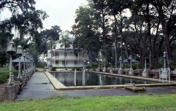 Photograph of Marabanong showing long narrow pool in front of Queen Anne-style house.