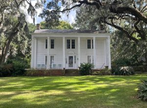 Photo of two story white house with columned porch.