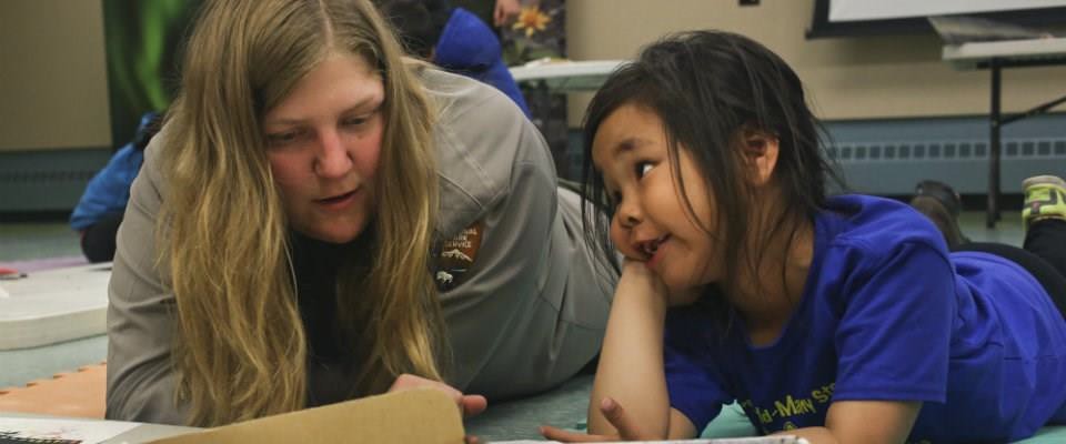 A woman instructing a girl on vocabulary.