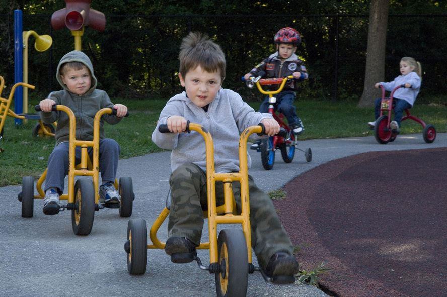 Children riding tricycles together.