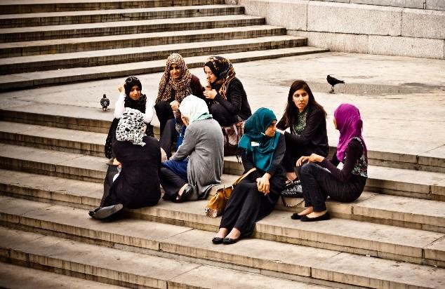 Muslim girls sitting on steps talking to their friends.