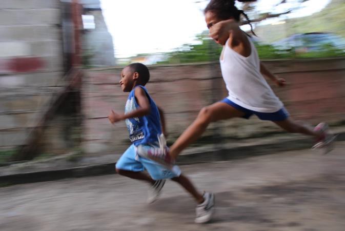 Two children running down the street in Carenage,